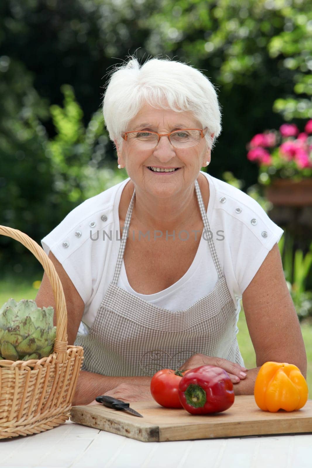Closeup of elderly woman in garden with basket of fresh vegetables