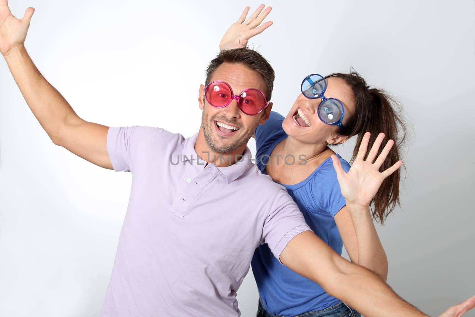Couple wearing colored glasses having fun on white background
