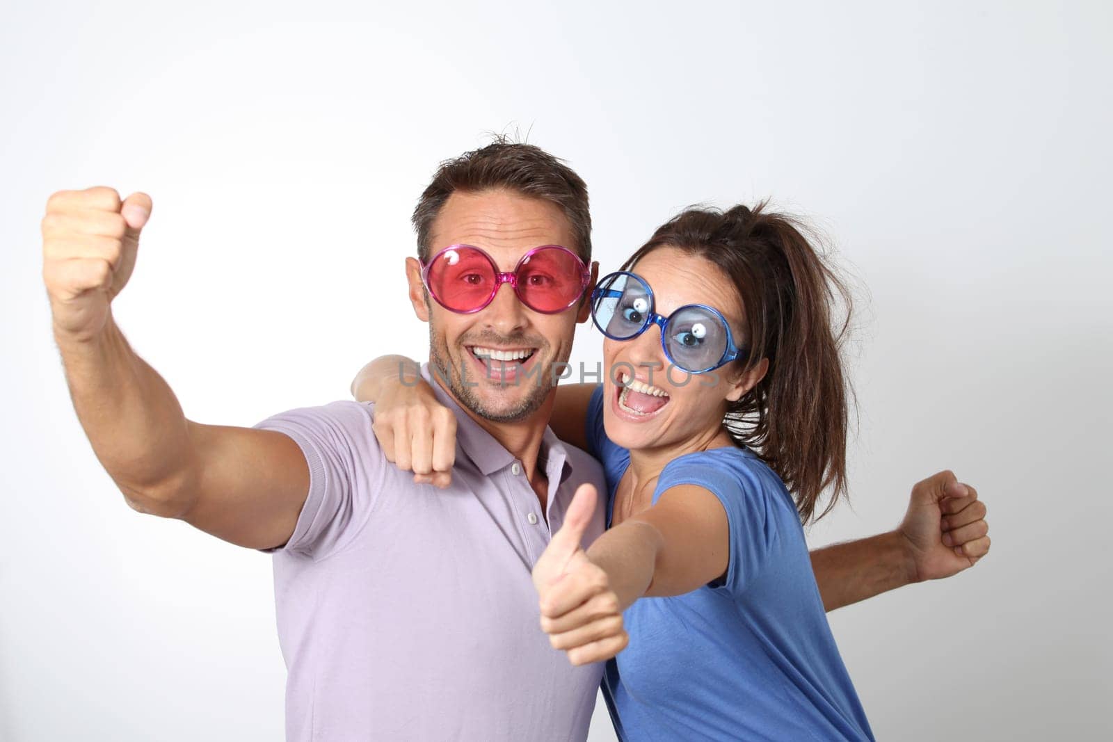Couple wearing colored glasses having fun on white background