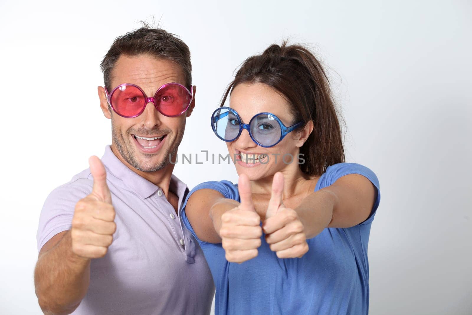Couple wearing colored glasses having fun on white background