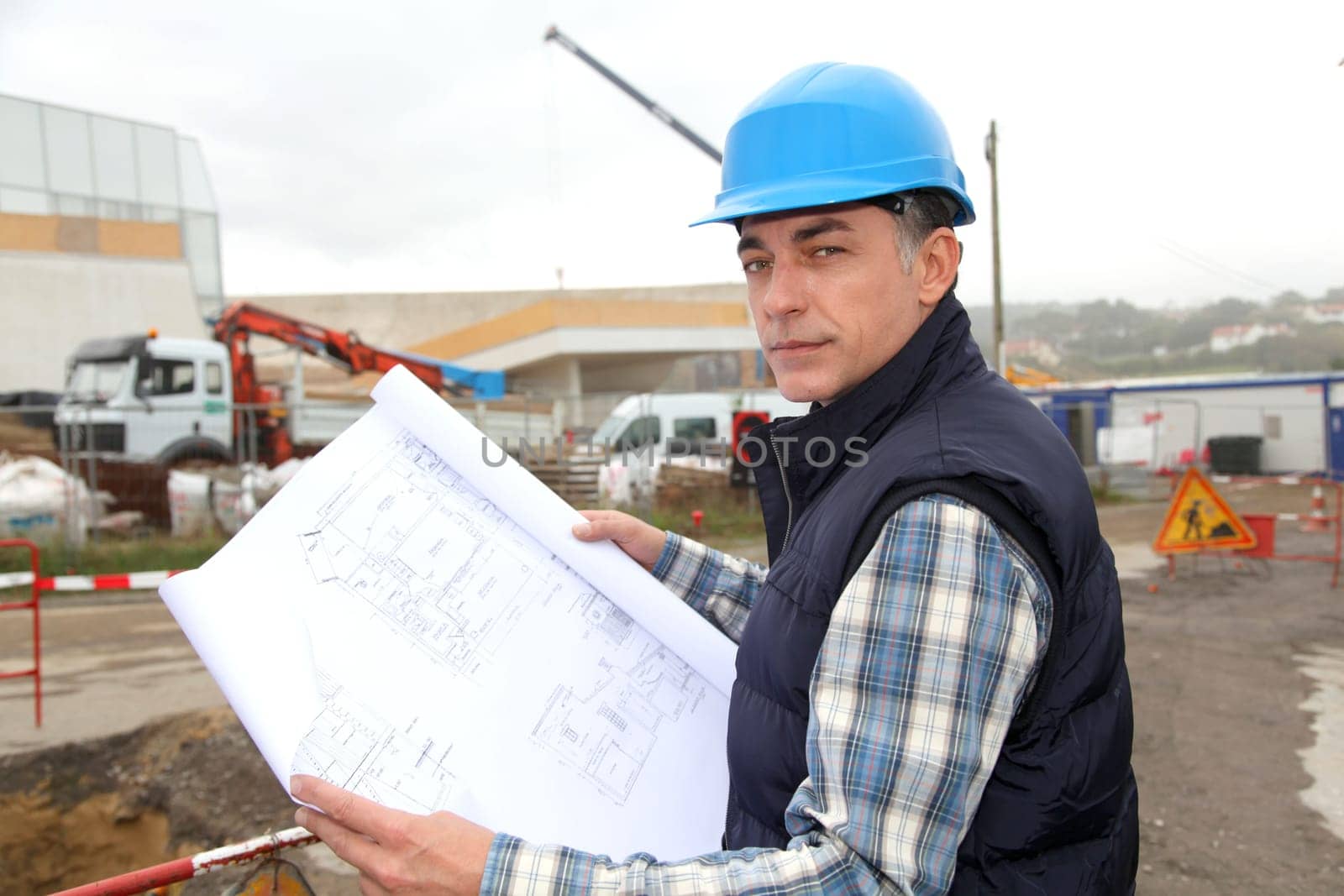 Engineer on construction site with building plan
