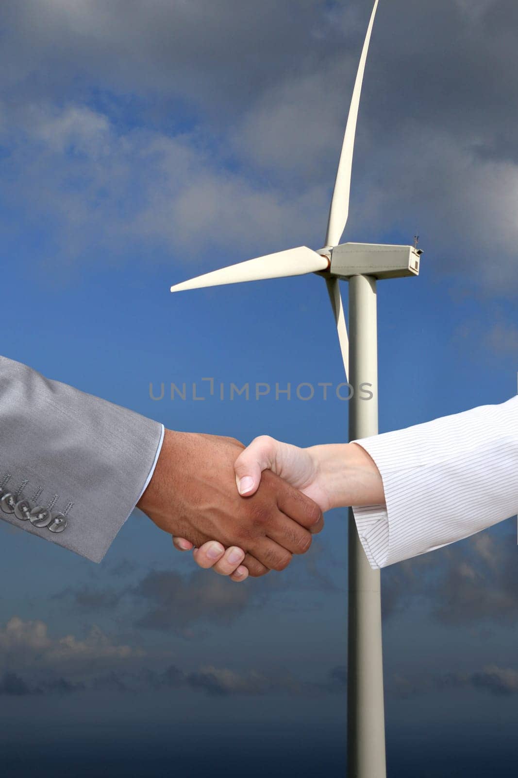Business hanshake in front of wind turbine