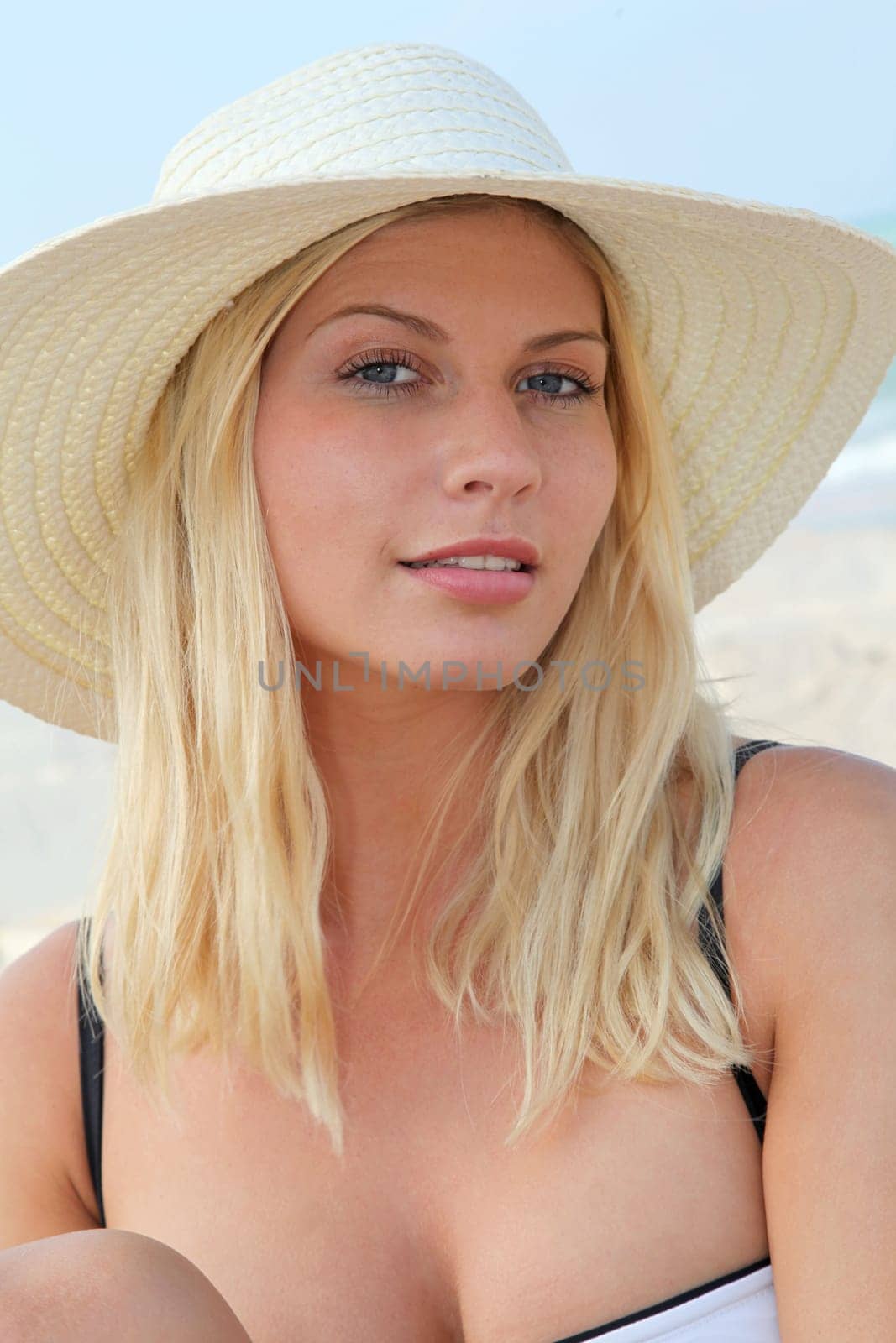 Closeup of beautiful blond woman wearing hat at the beach