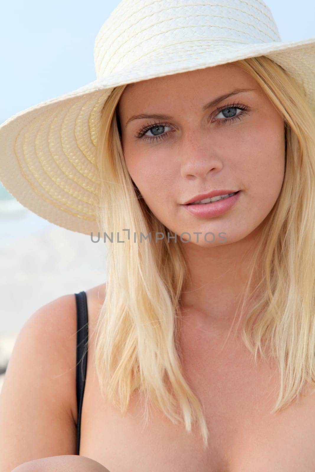 Closeup of beautiful blond woman wearing hat at the beach