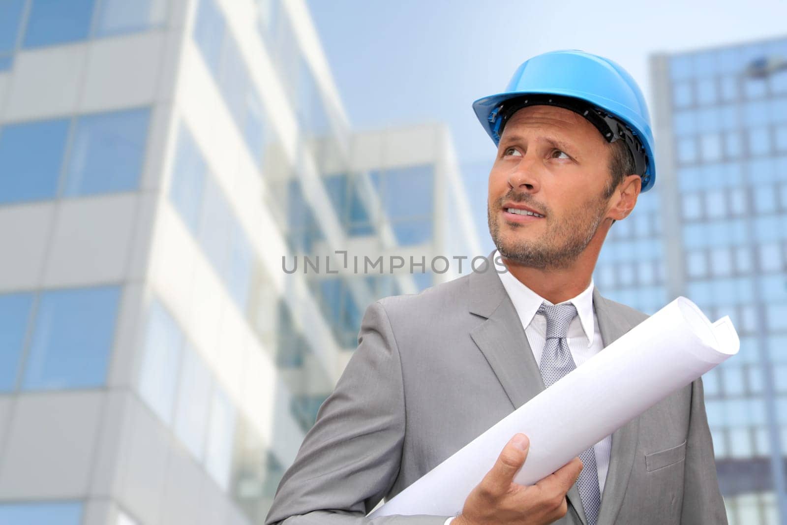 Engineer in front of modern building with plan