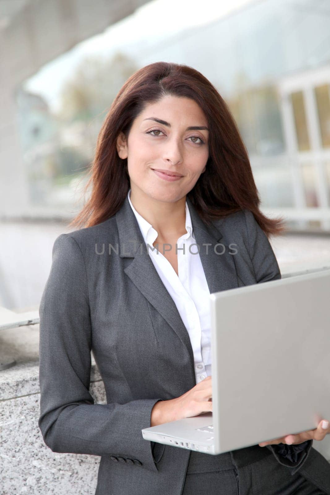 Businesswoman with laptop computer standing outside