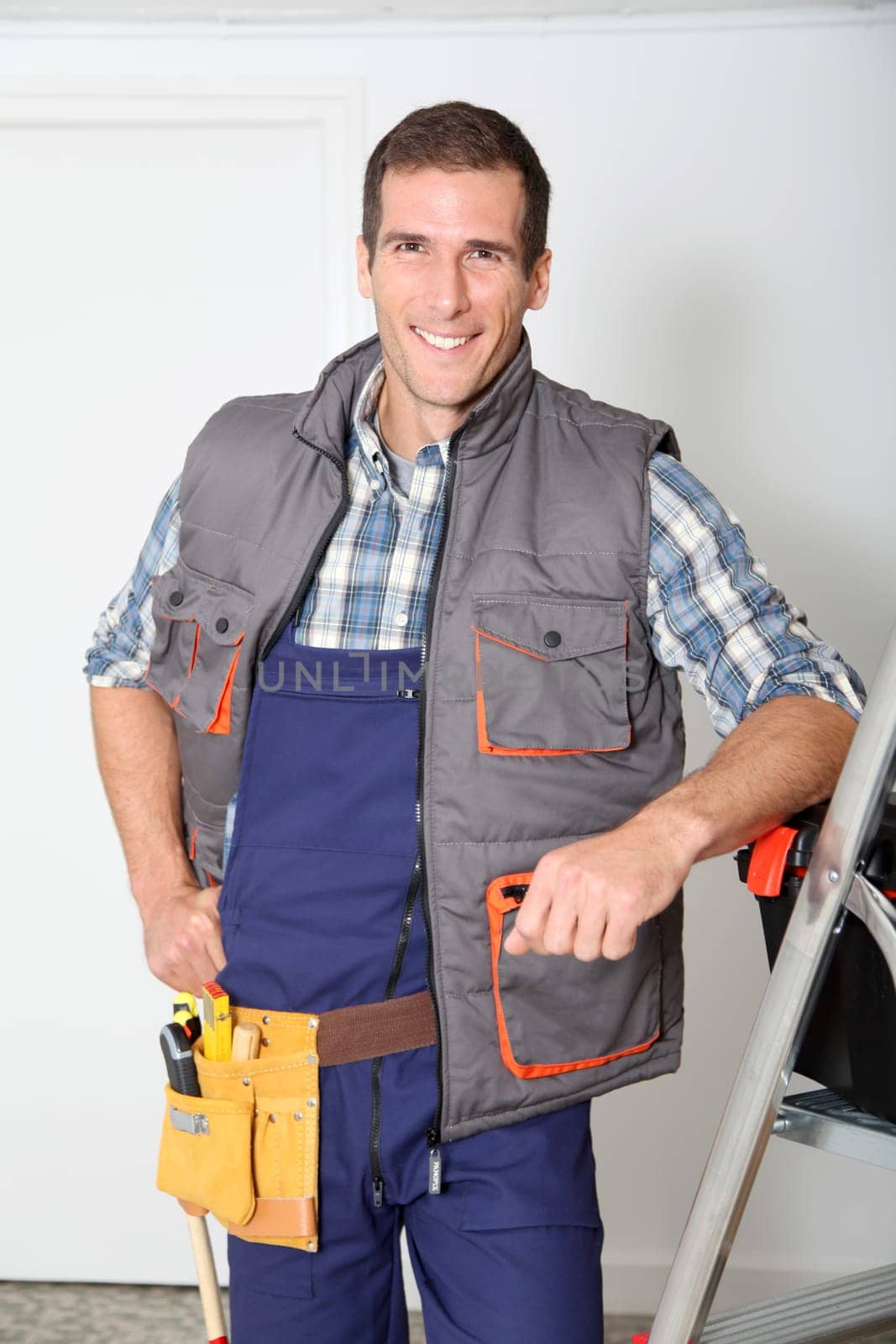 Smiling electrician man standing by scale