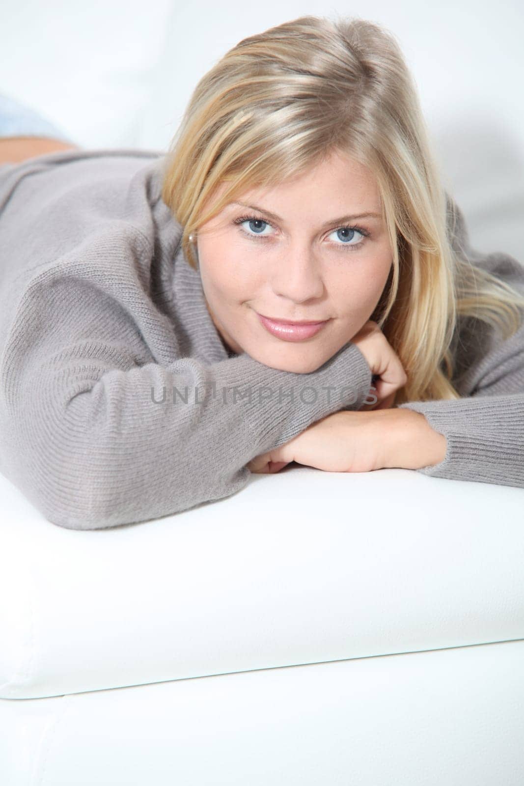 Smiling beautiful blond woman laying on sofa