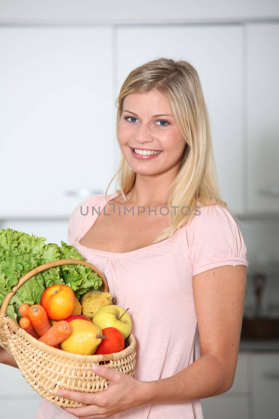Smiling woman holding basket of organic food