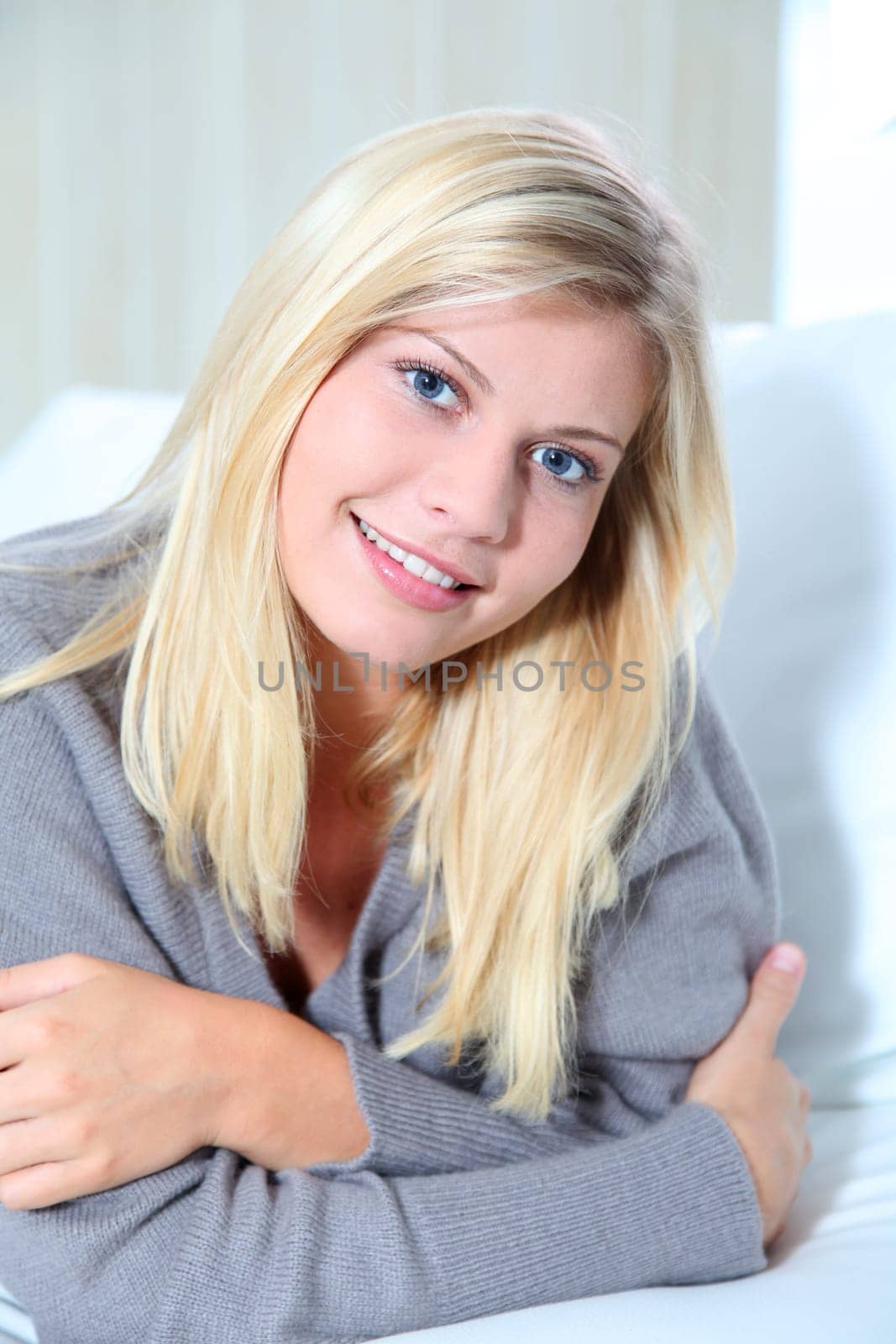 Smiling beautiful blond woman laying on sofa