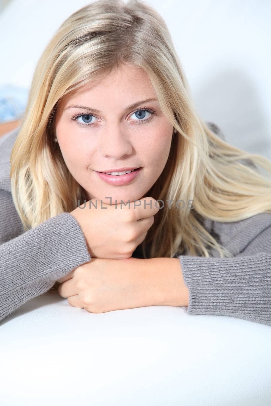 Smiling beautiful blond woman laying on sofa