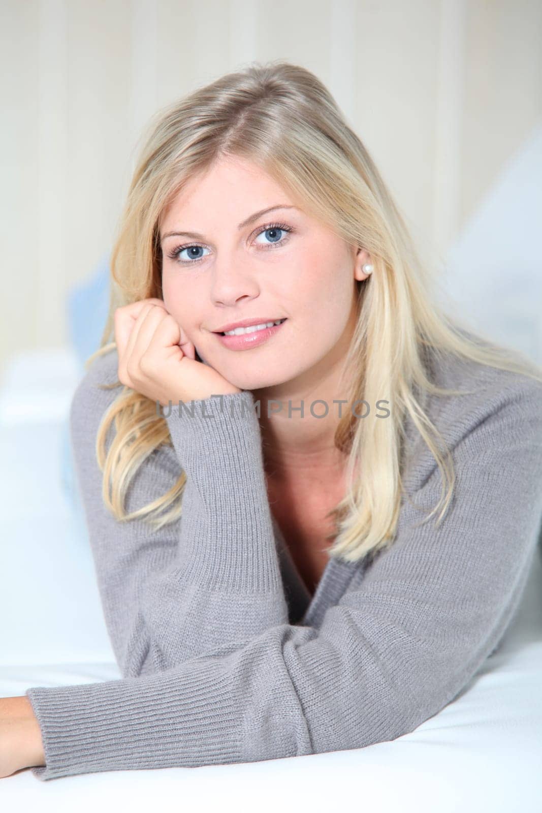 Smiling beautiful blond woman laying on sofa