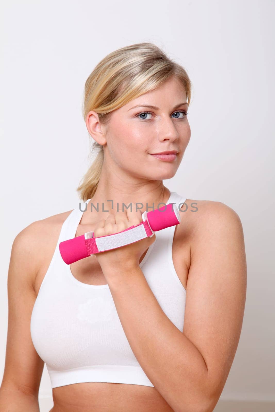 Beautiful blond woman lifting dumbbells in fitness gym