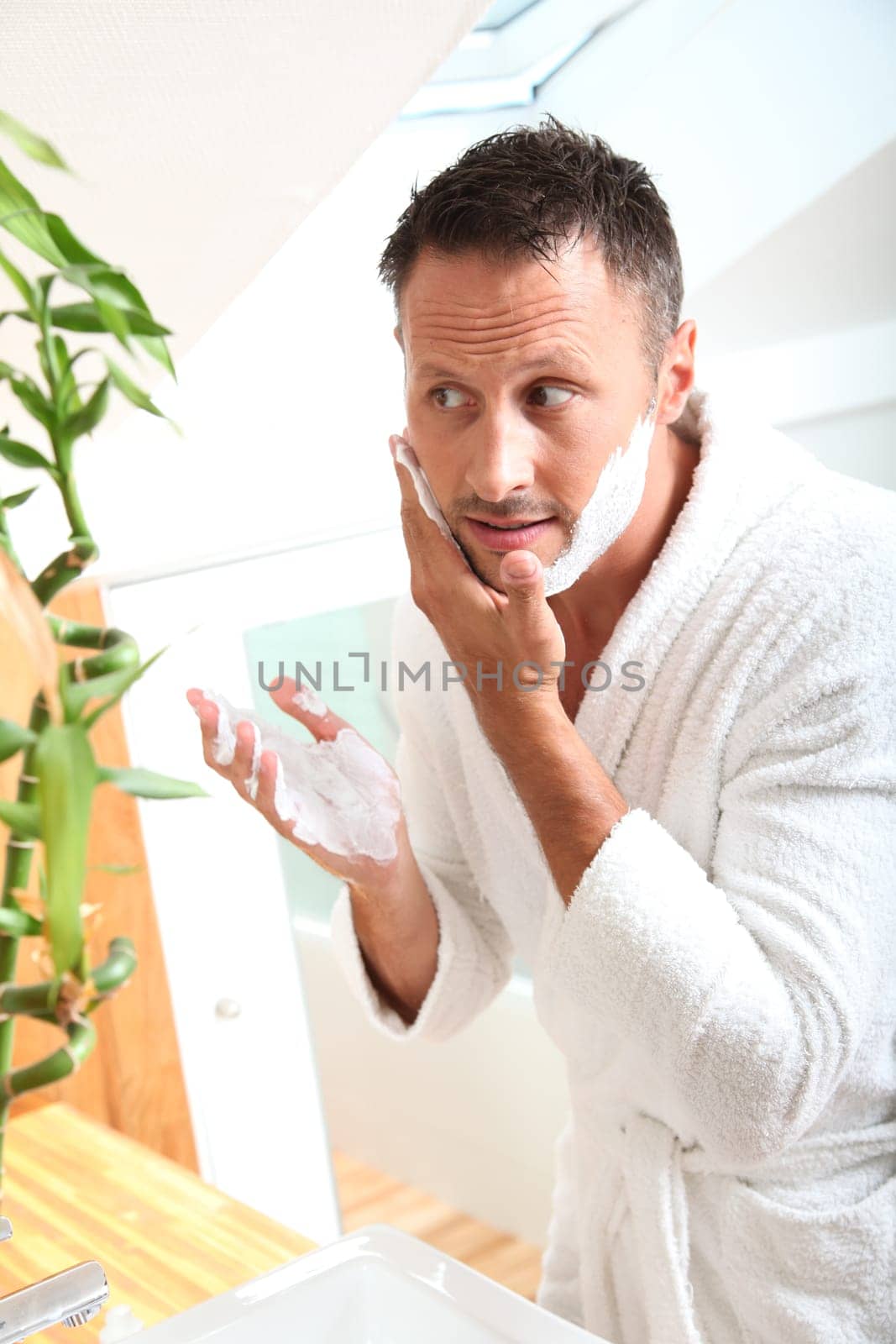 Handsome man shaving in bathroom