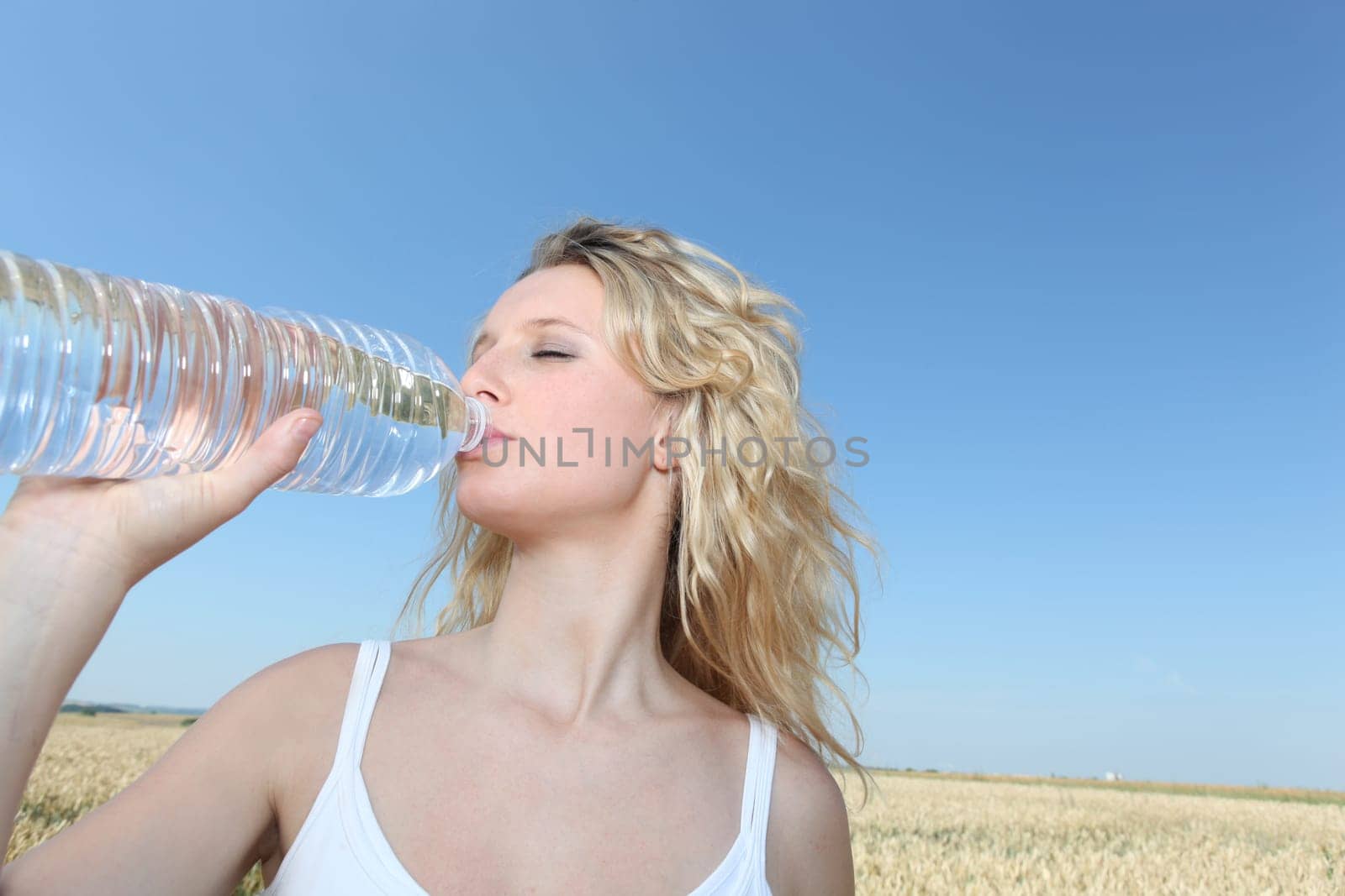beautiful blond woman drinking water fom bottle