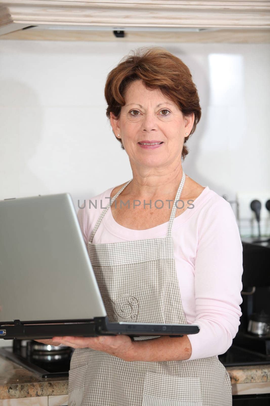 Closeup of senior woman in kitchen with laptop computer