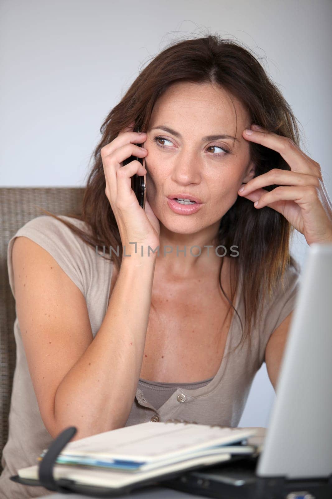 Woman working at home on laptop computer with telephone