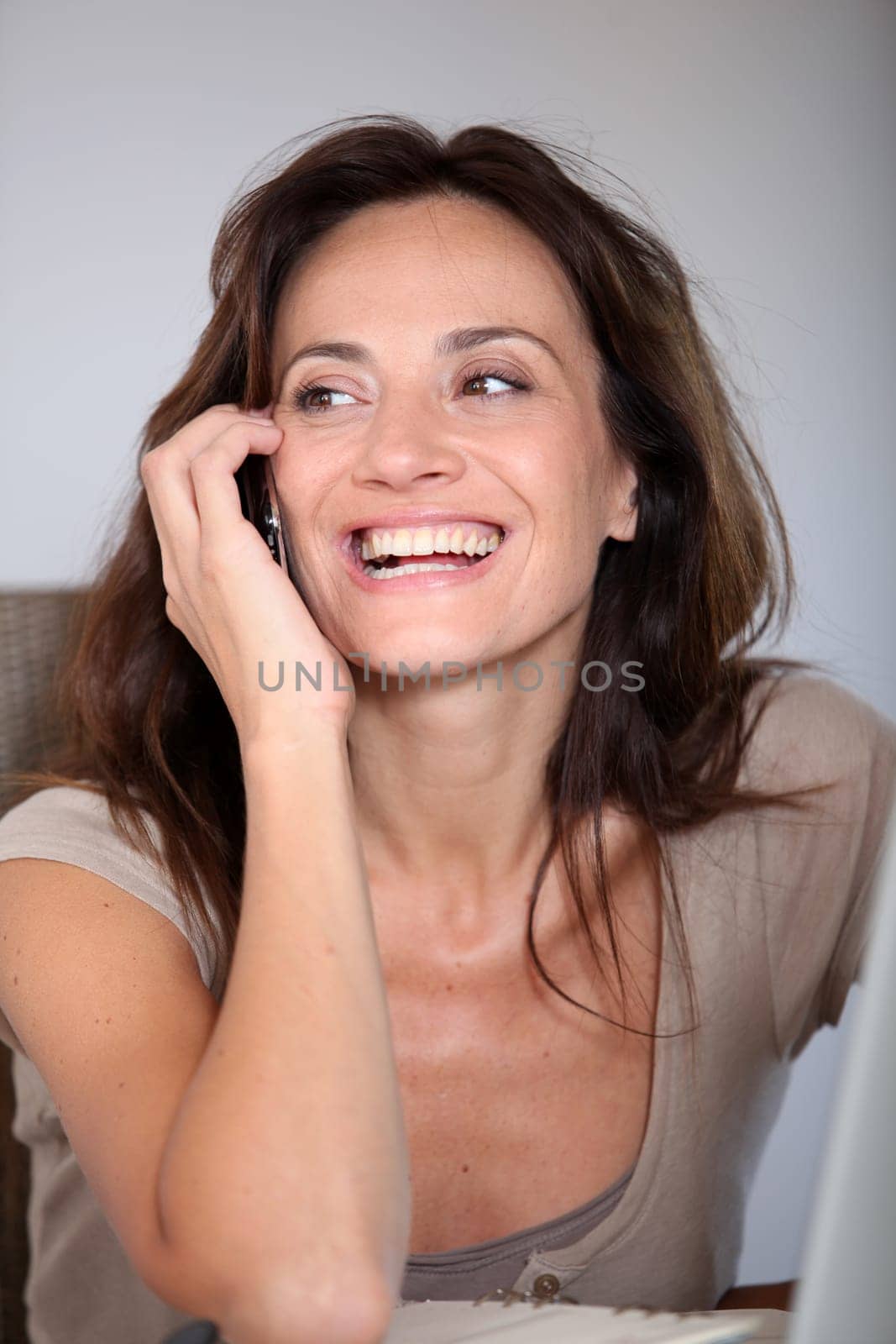Woman working at home on laptop computer with telephone