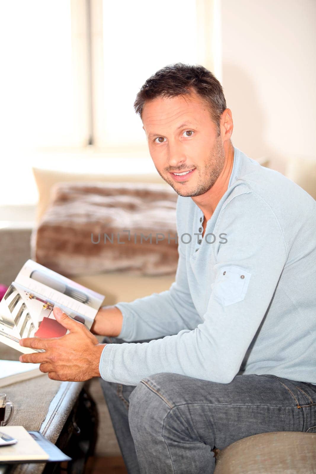 Man at home sitting in couch with book