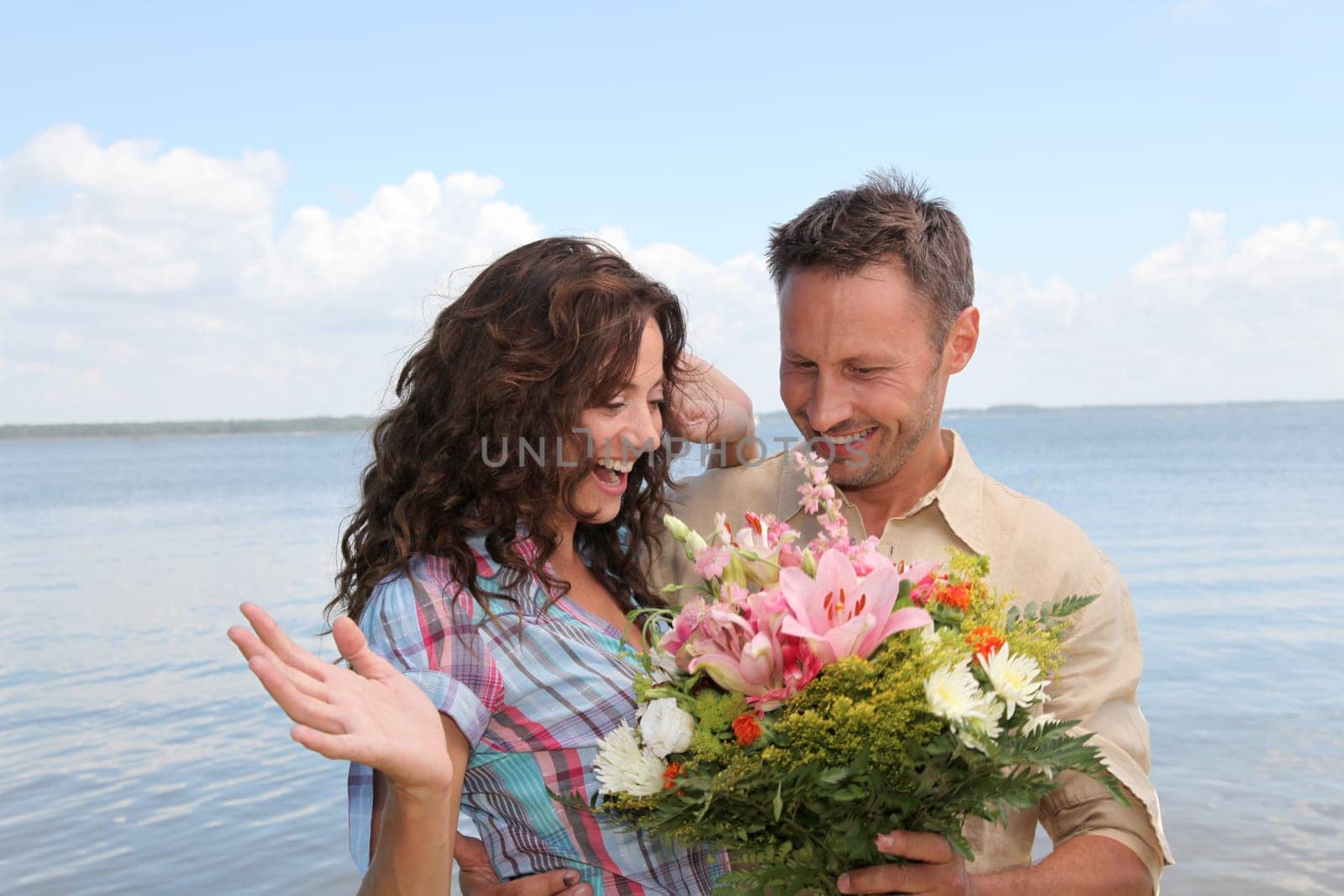 Man surprising woman with bunch of flowers