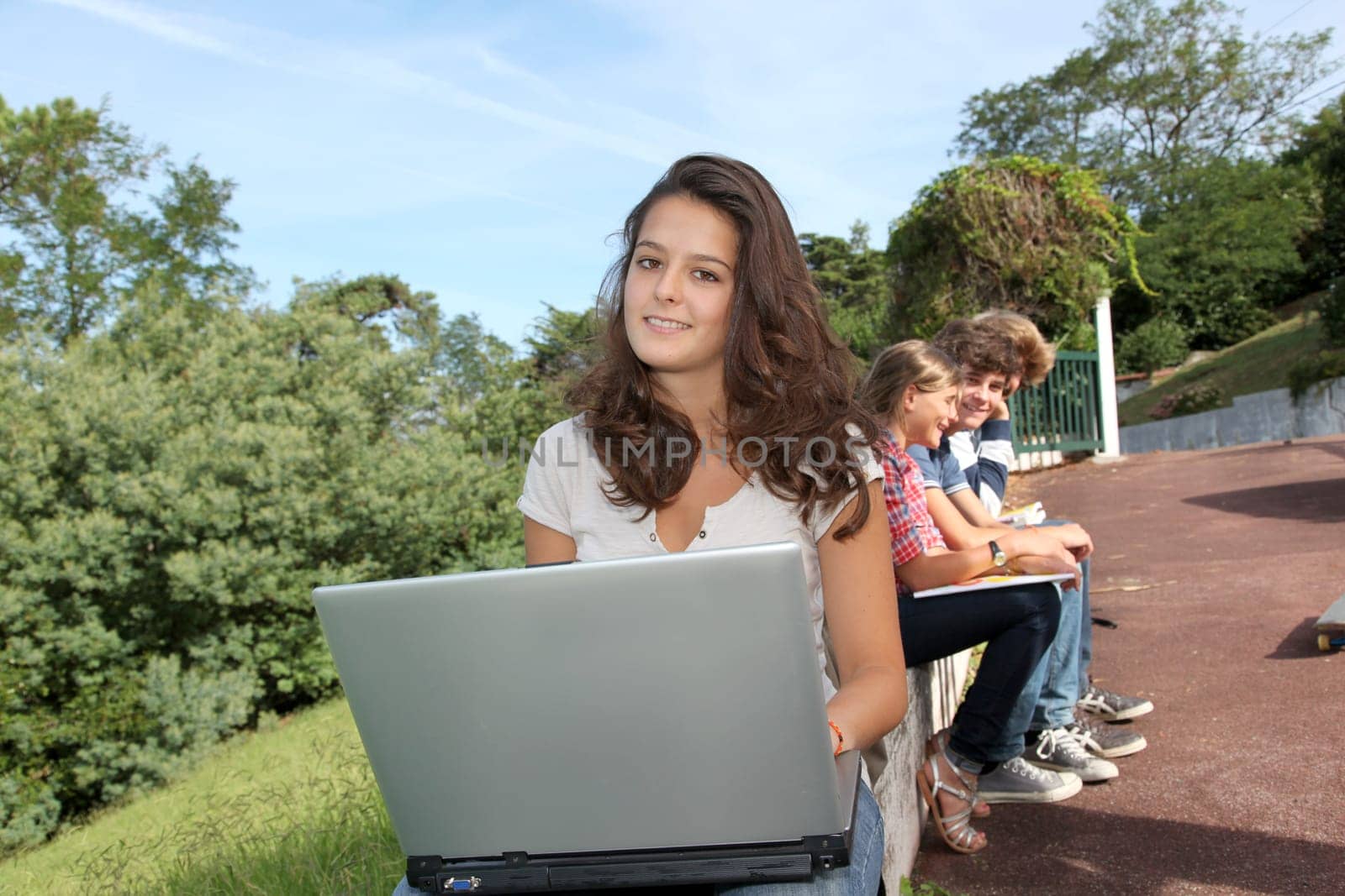 Teenagers sitting outside with laptop computer