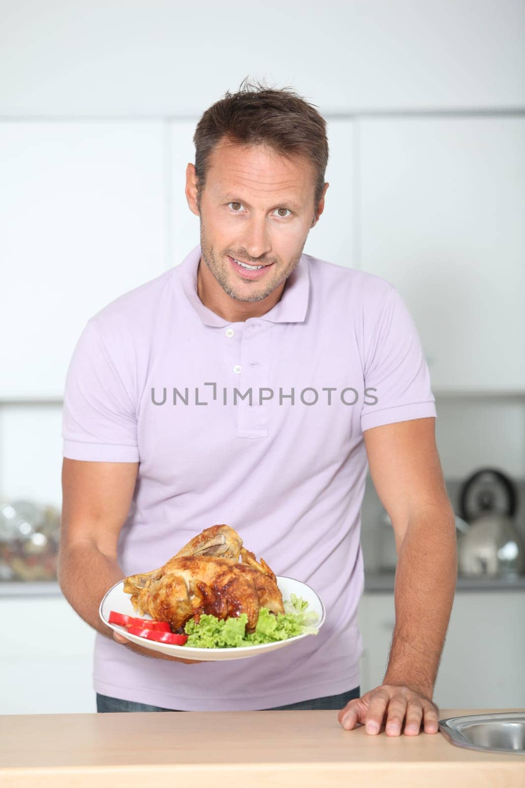 Man in kitchen with apron cooking chicken