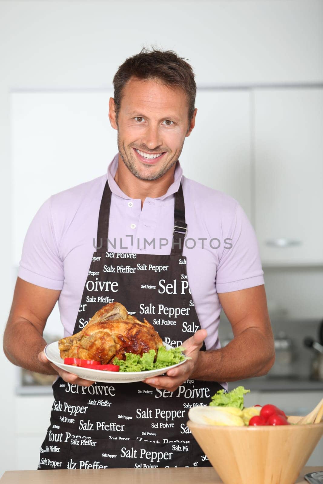 Man in kitchen with apron cooking chicken