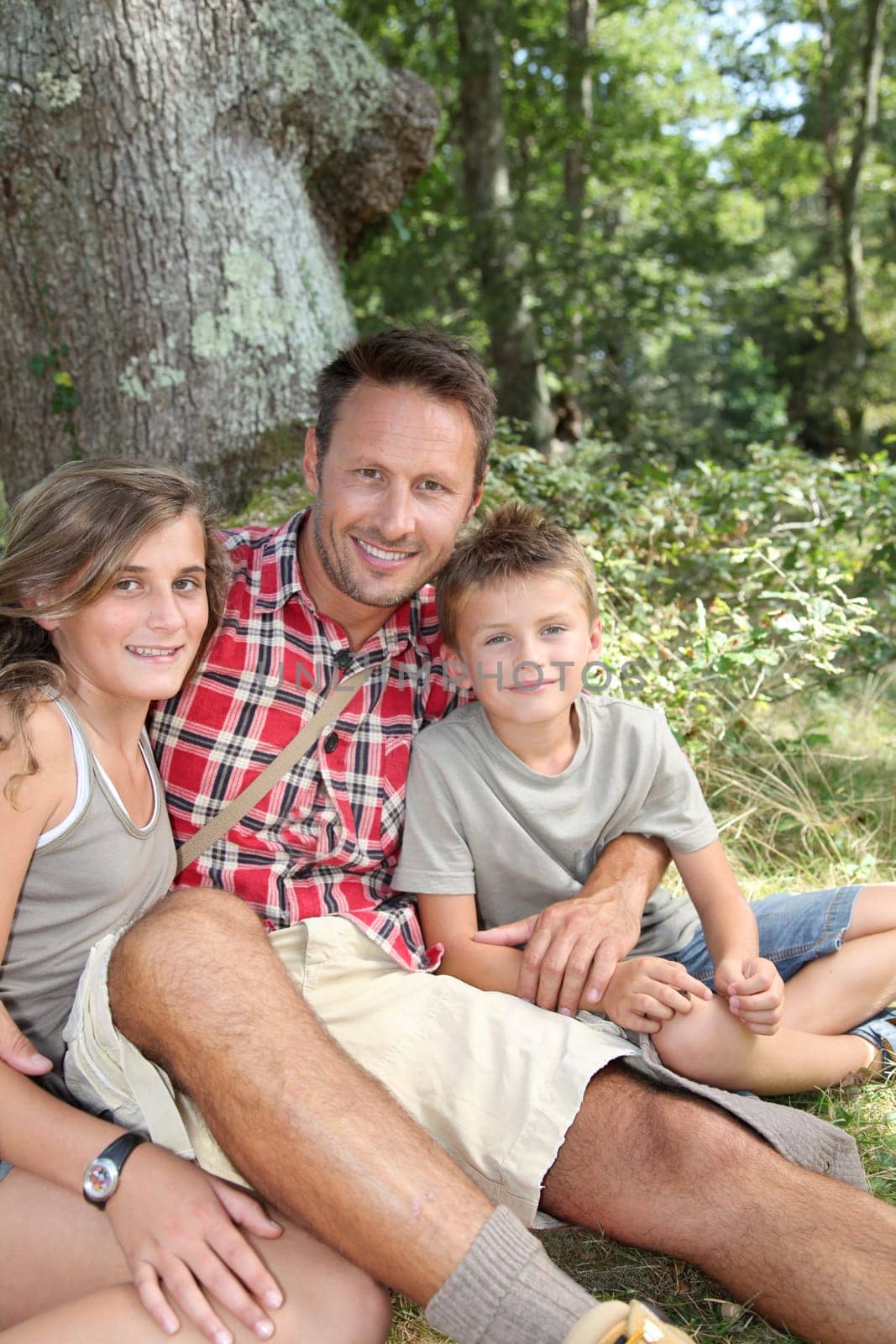 Father sitting by a tree with his children