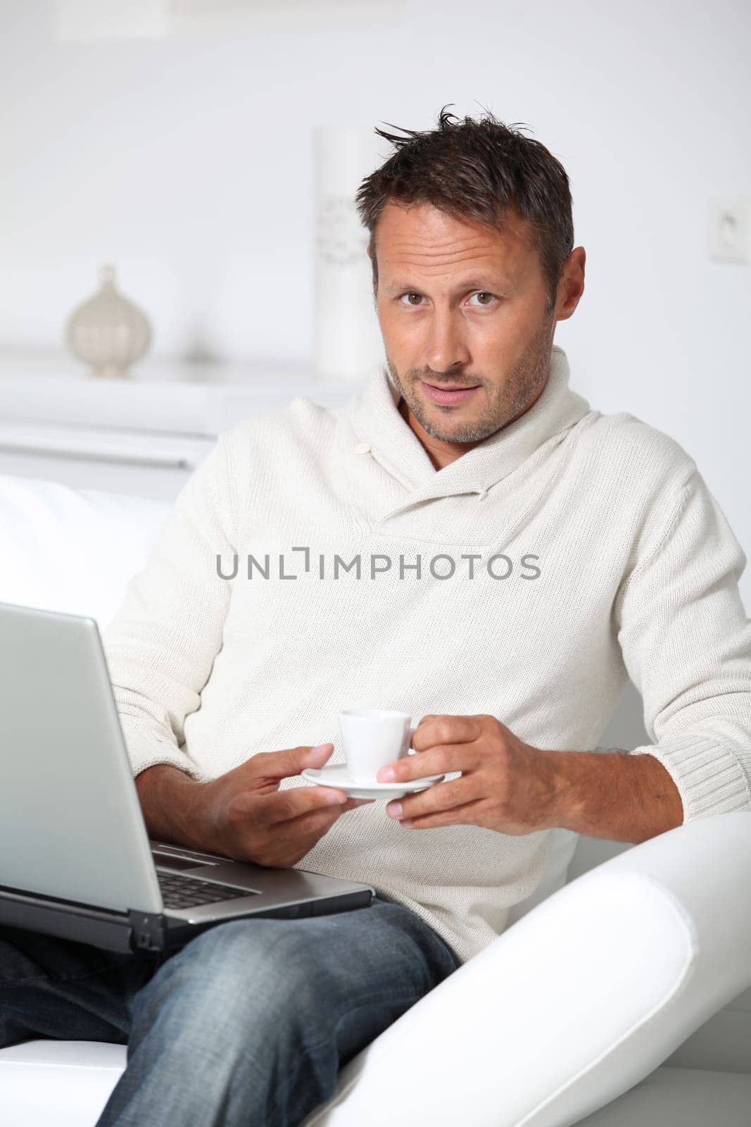 Man with laptop computer sitting in sofa