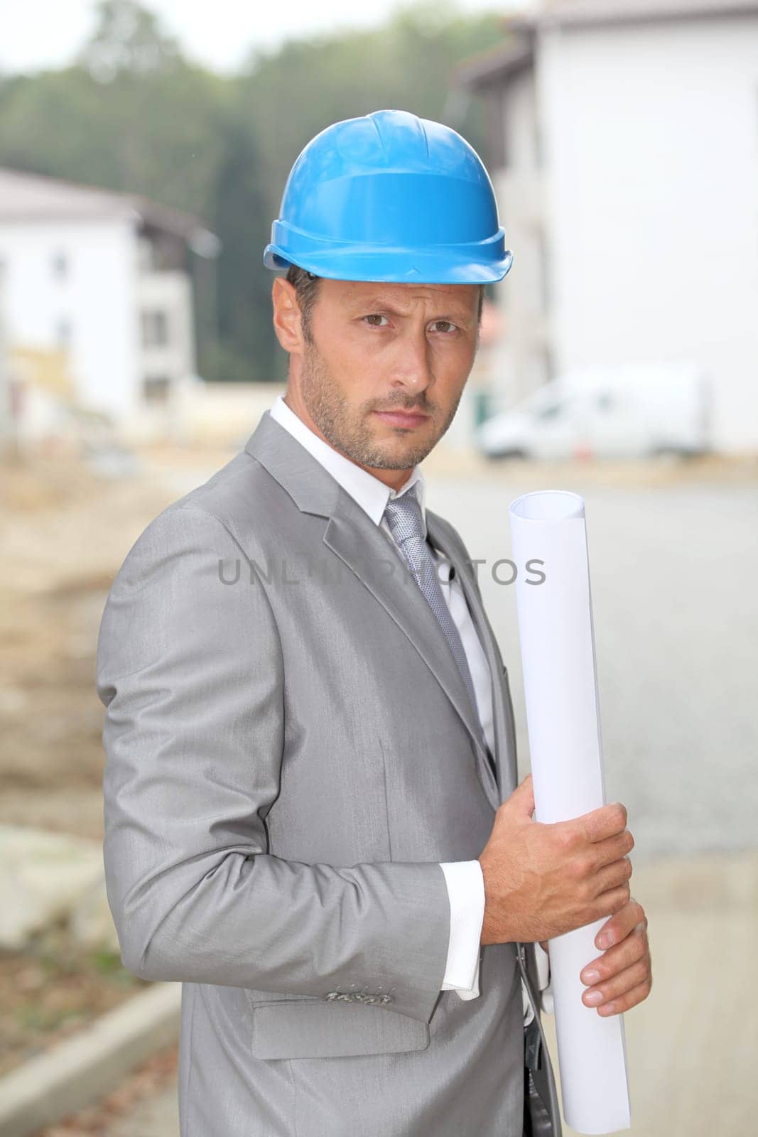 Businessman with helmet checking site under construction