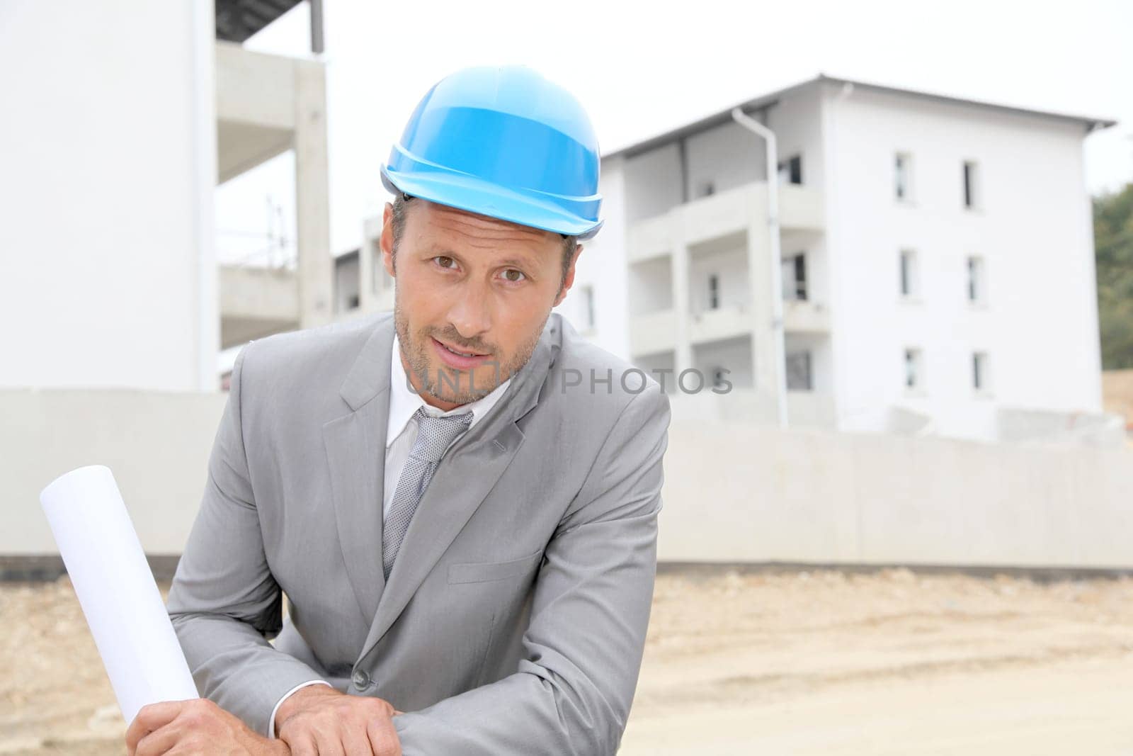 Businessman with helmet checking site under construction
