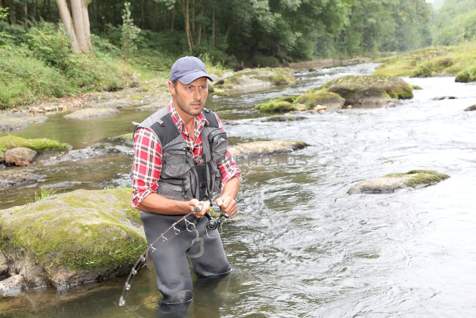 Fisherman in river with fishing rod