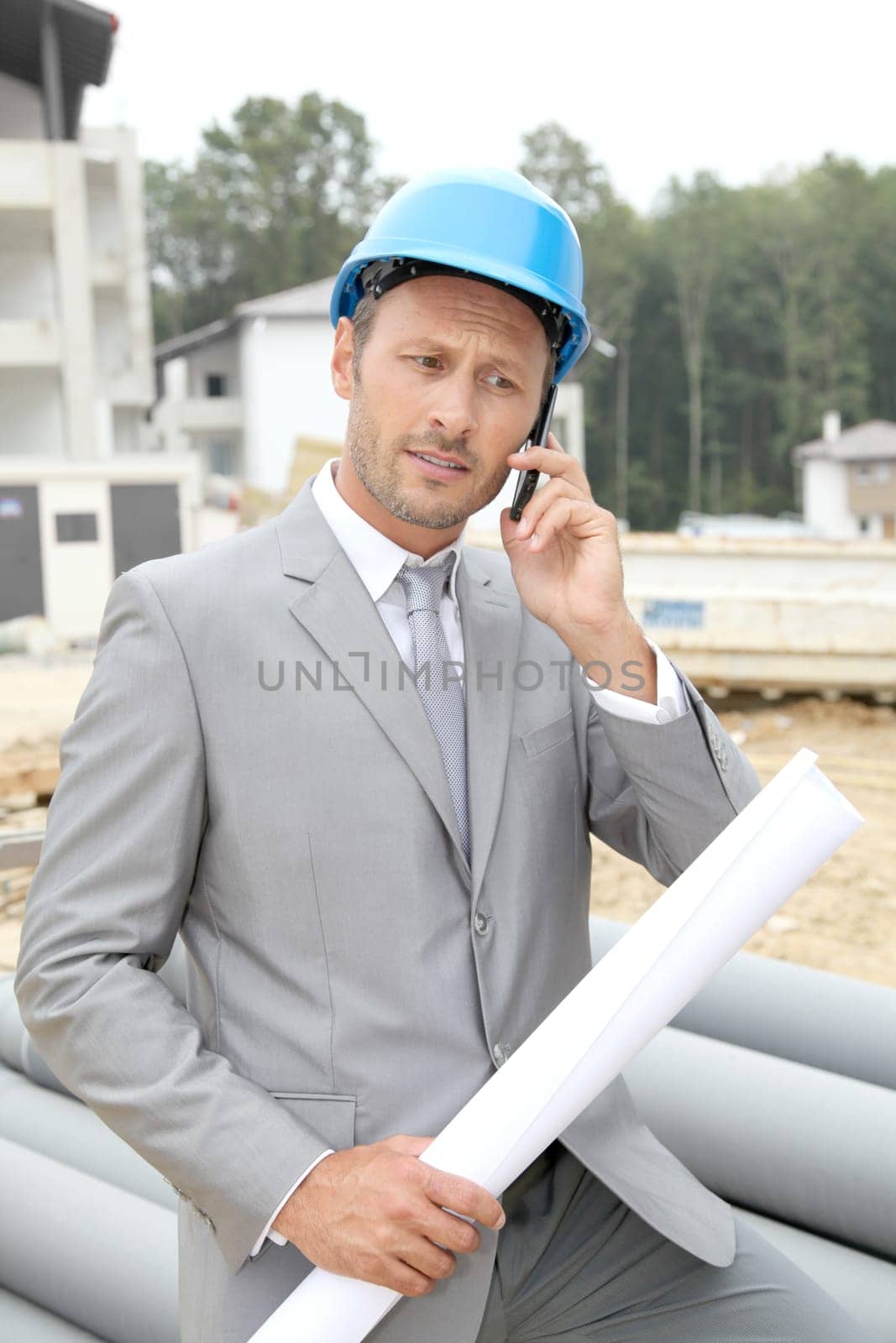 Businessman with helmet checking site under construction