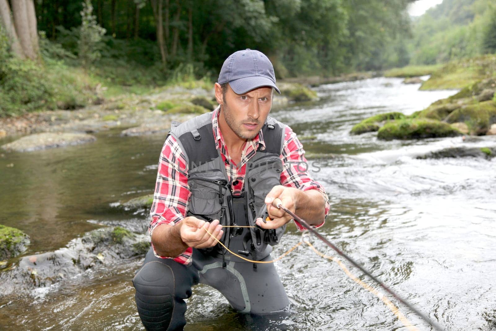 Fisherman in river with fly fishing rod
