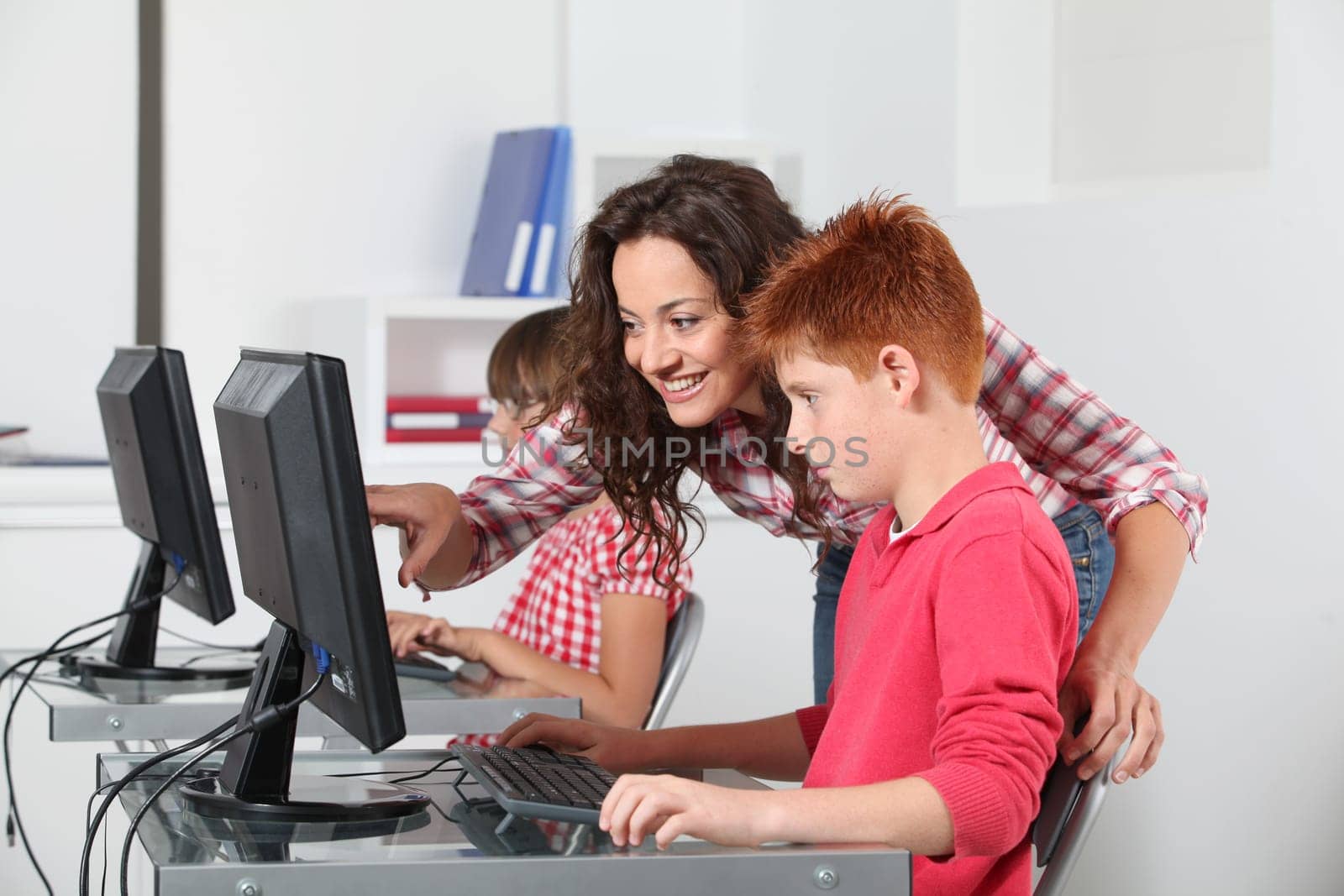 Teacher and children learning to use computer