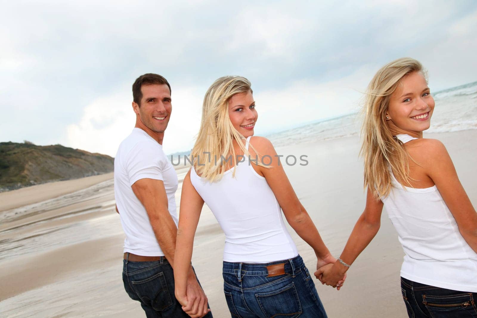 Family walking hand to hand on a sandy beach