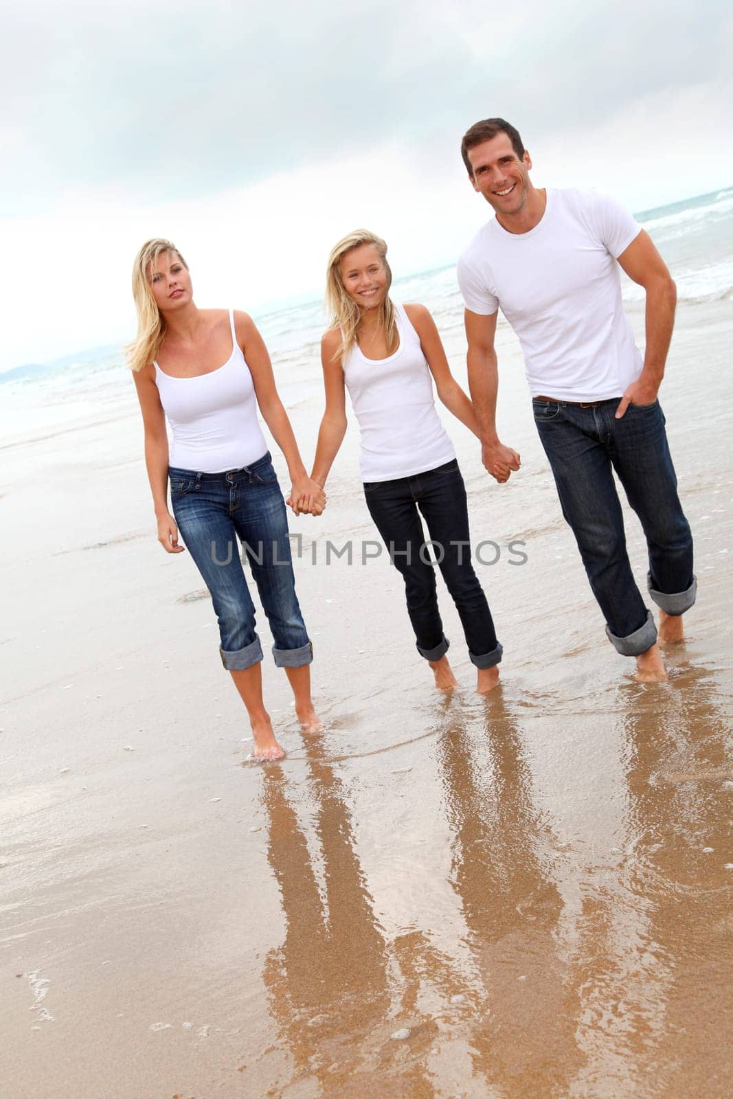 Family walking hand to hand on a sandy beach