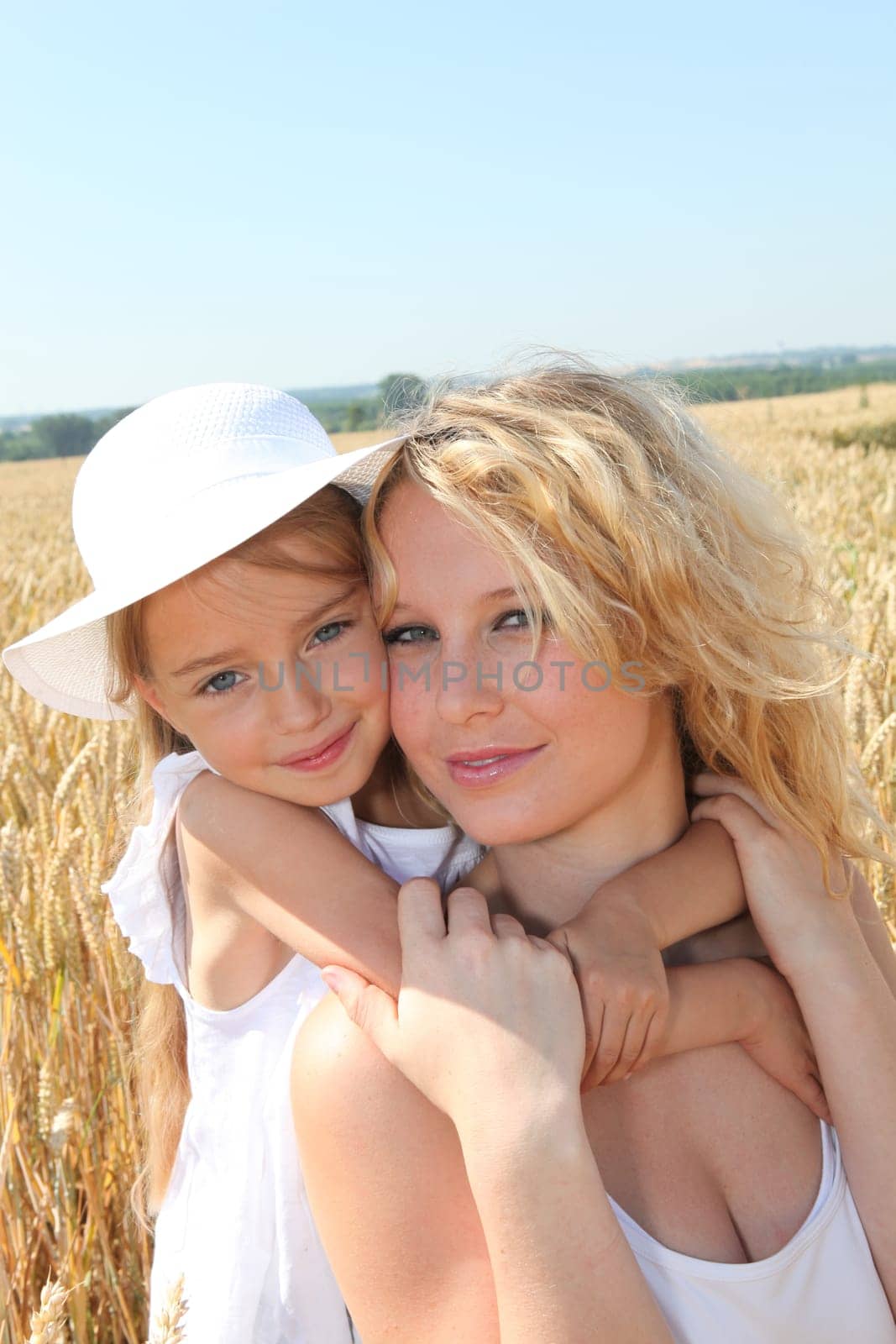 Mother and child in wheat field on sunny day