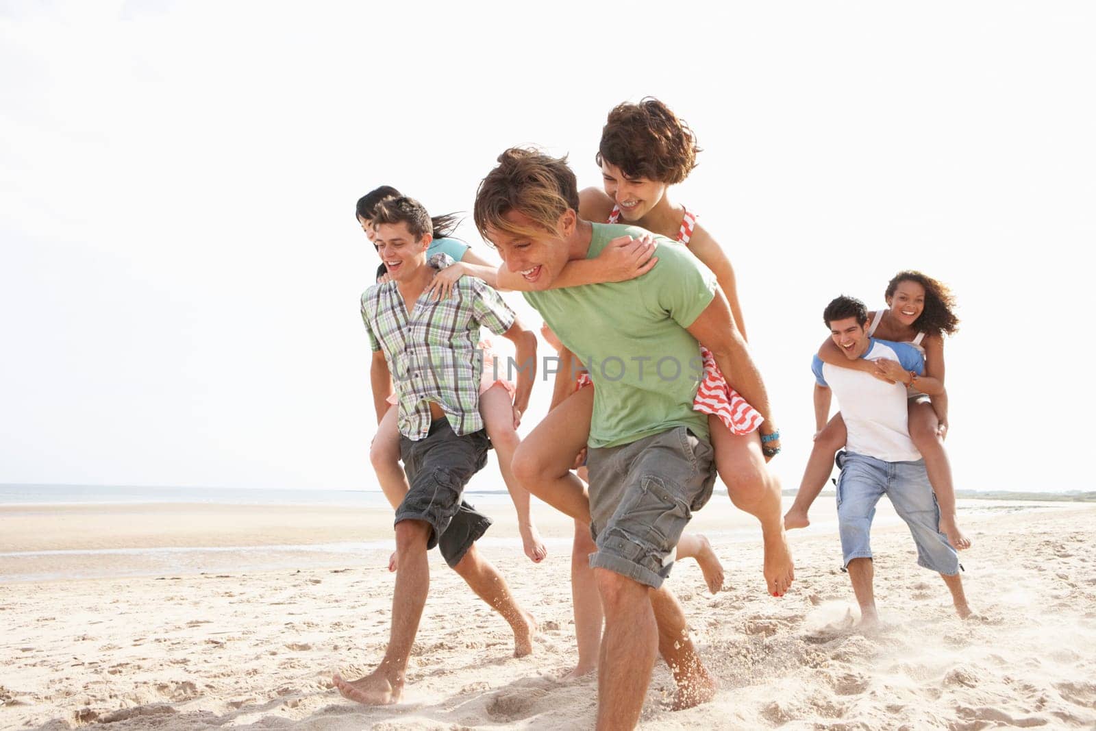 Group Of Friends Running Along Beach Together