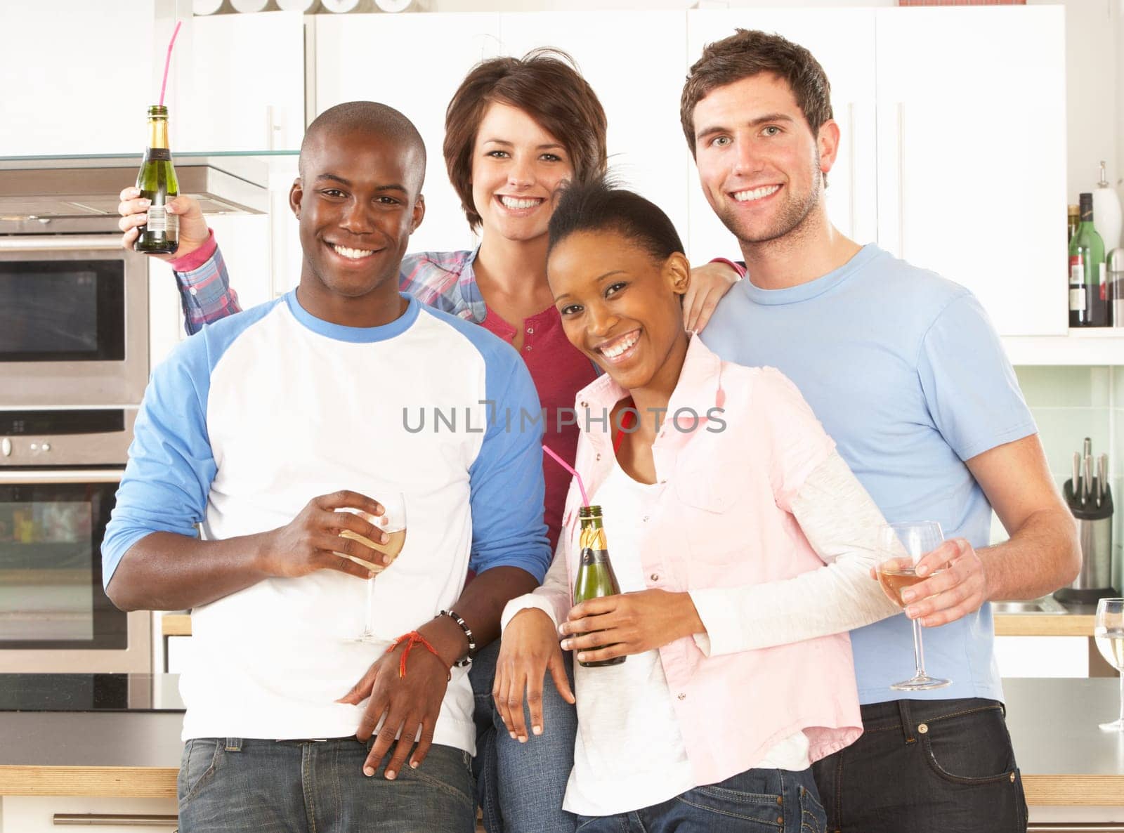 Group Of Young Friends Enjoying Drink In Modern Kitchen