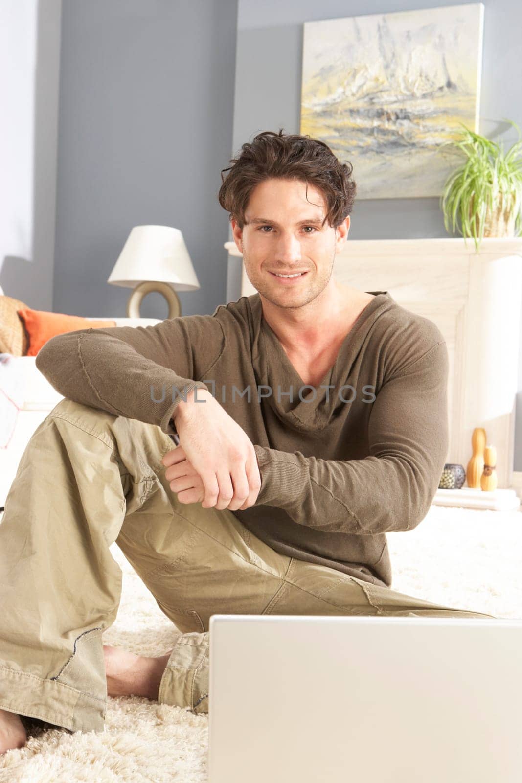 Man Using Laptop Relaxing Sitting On Rug At Home
