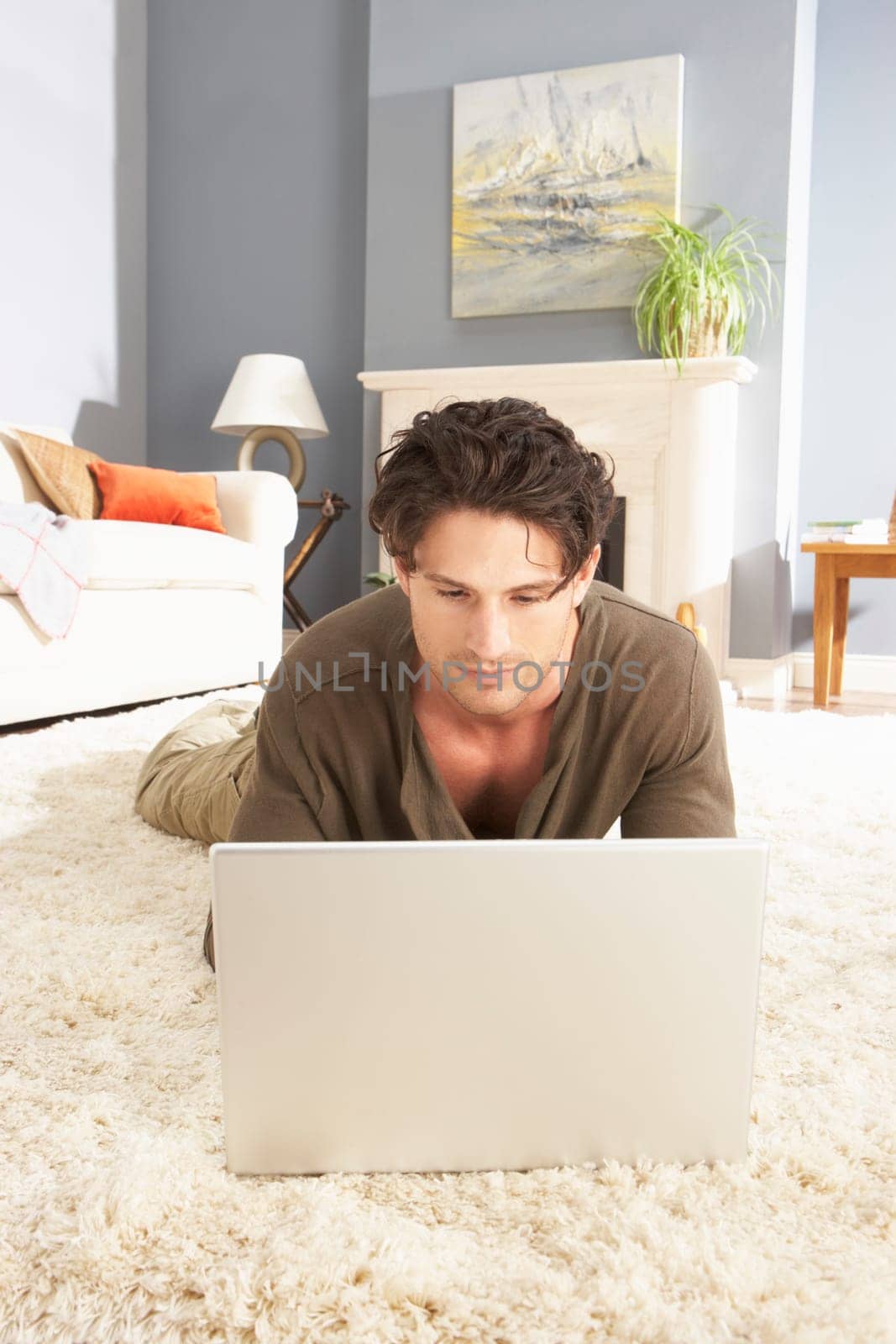 Man Using Laptop Relaxing Laying On Rug At Home