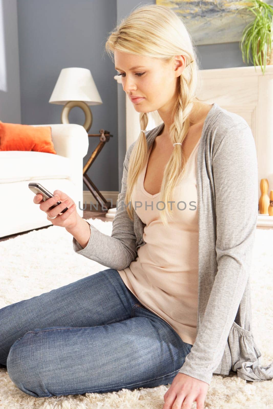 Woman Using Mobile Phone Relaxing Sitting On Rug At Home