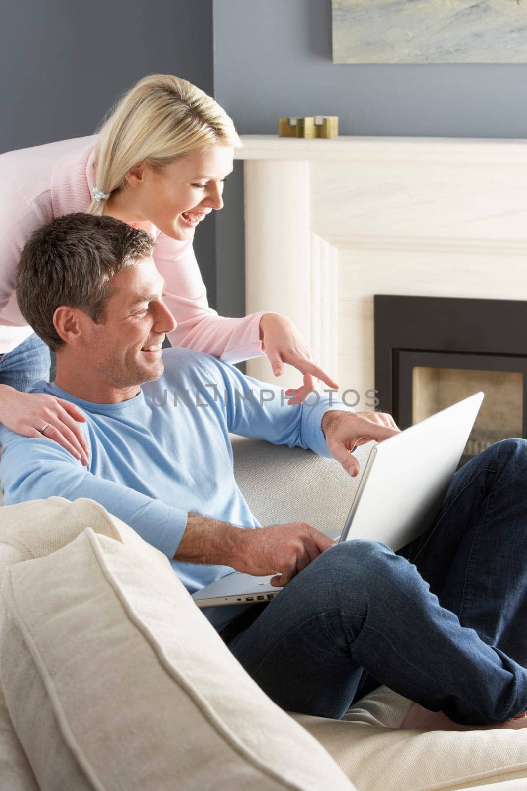 Couple Using Laptop Relaxing Sitting On Sofa At Home