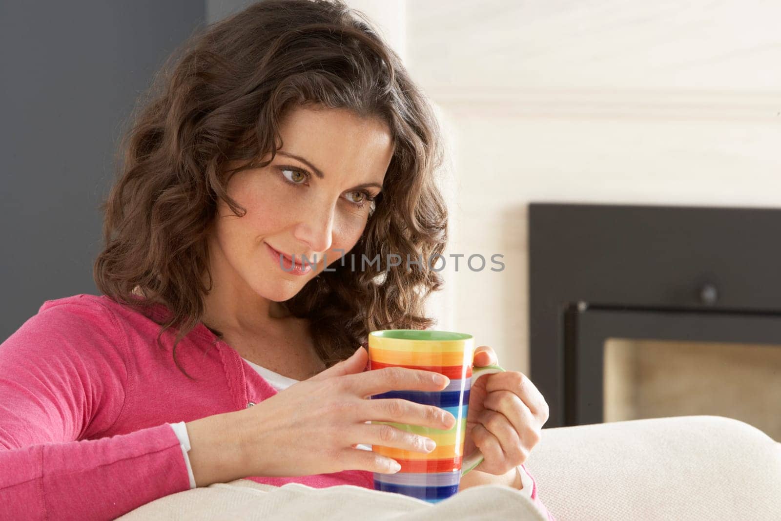 Woman Relaxing On Sofa At Home Drinking Cup Of Coffee