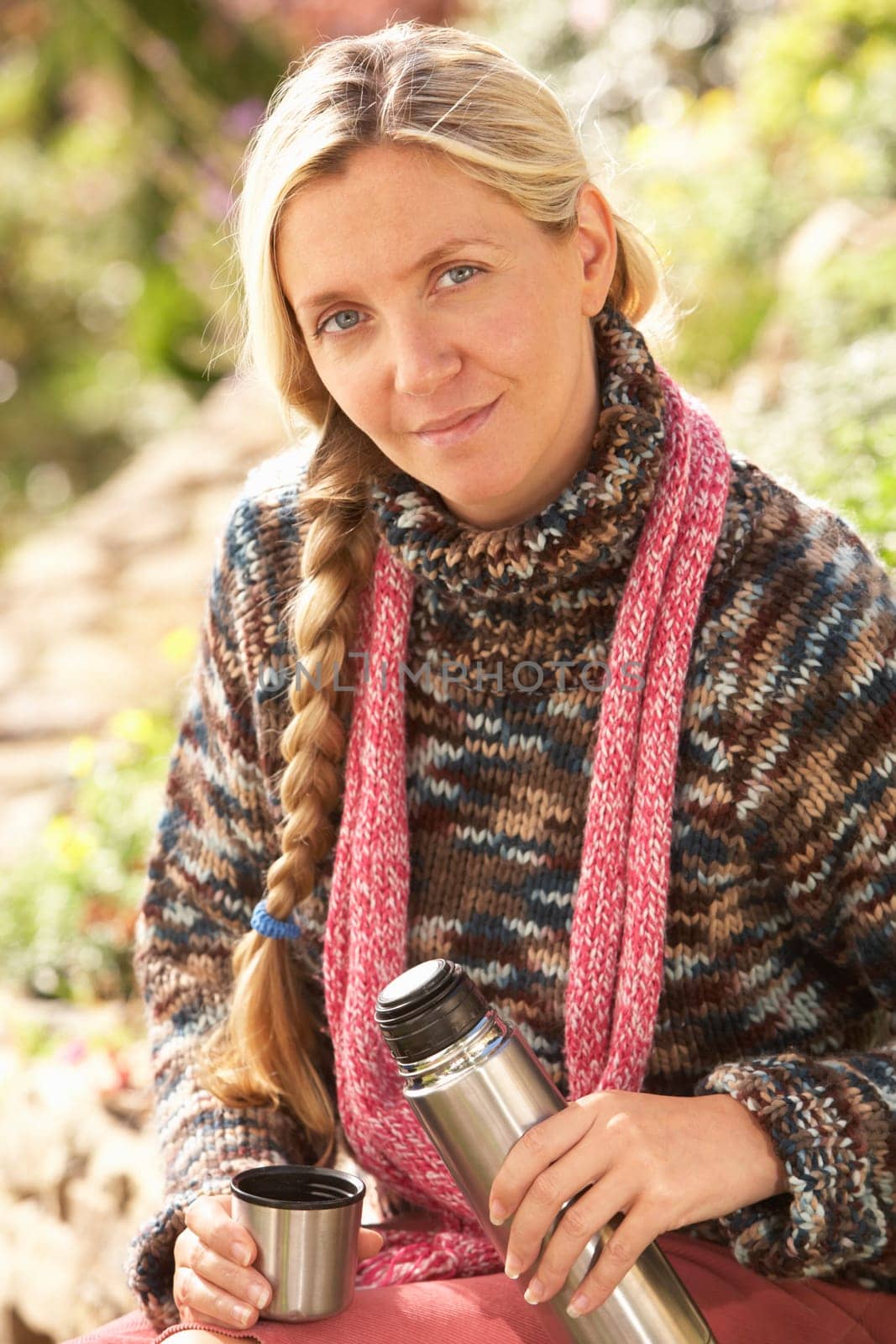 Young Woman Relaxing With Thermos Flask In Autumn Landscape