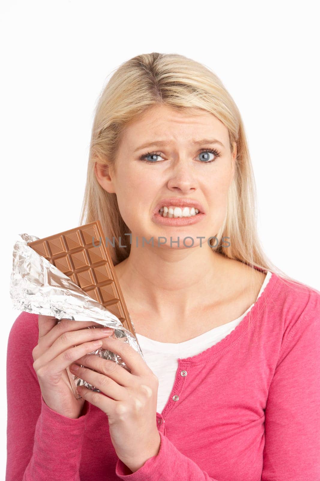 Guilty Looking Young Woman Eating Big Bar Of Chocolate In Studio