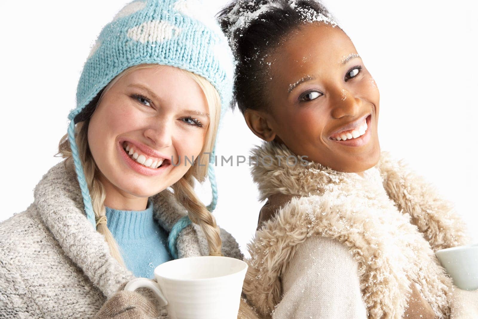 Two Young Women Wearing Warm Winter Clothes Holding Snowball In Studio