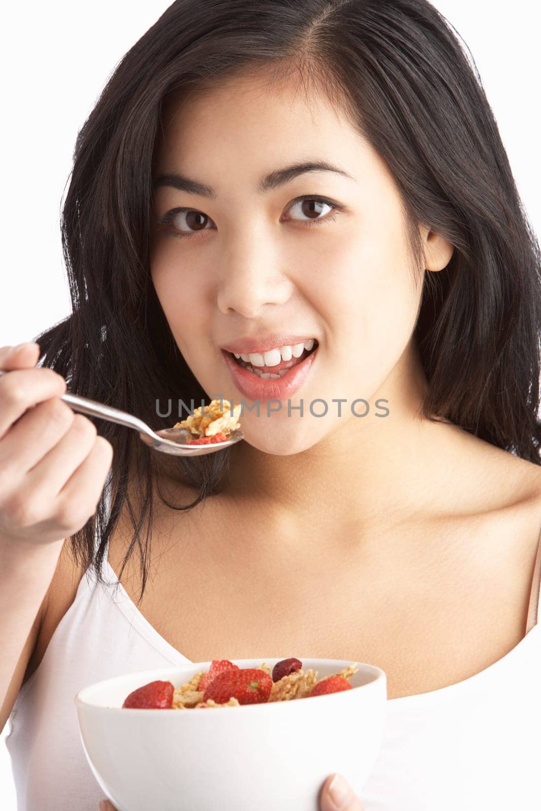 Young Woman Eating Bowl Of Healthy Breakfast Cereal In Studio