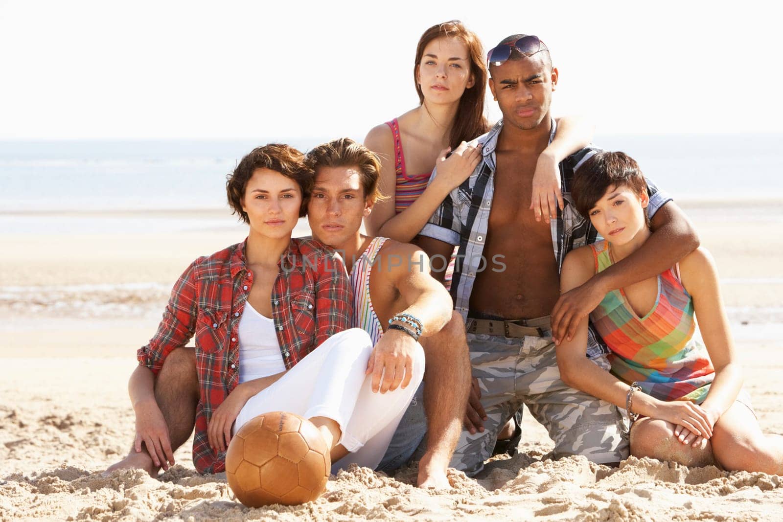 Group Of Friends Relaxing On Beach With Football Together